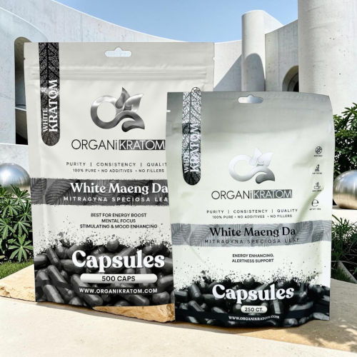 Two packages of White Maeng Da capsules in a garden setting.