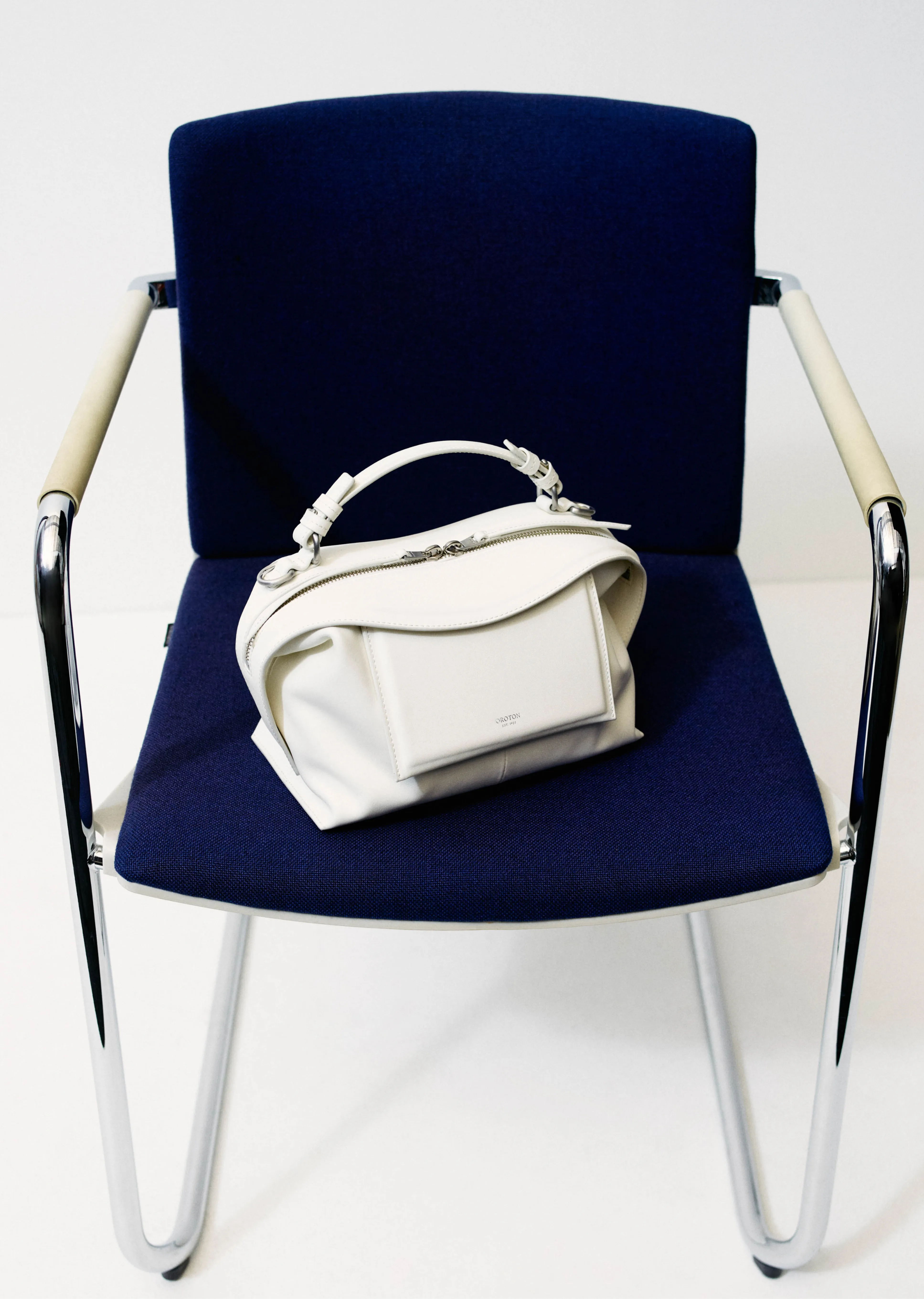 A white handbag resting on a blue chair.