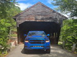 Blue RAM 1500 parked in front of historic wooden covered bridge in Albany