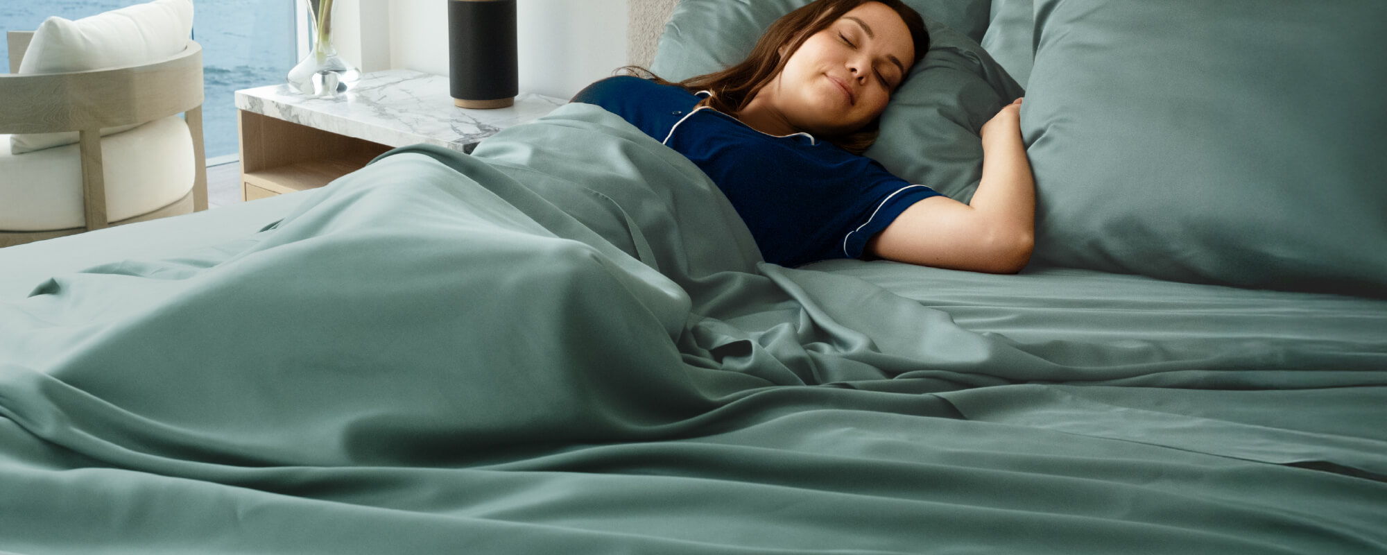 a woman lying in a bed with teal bamboo sheets