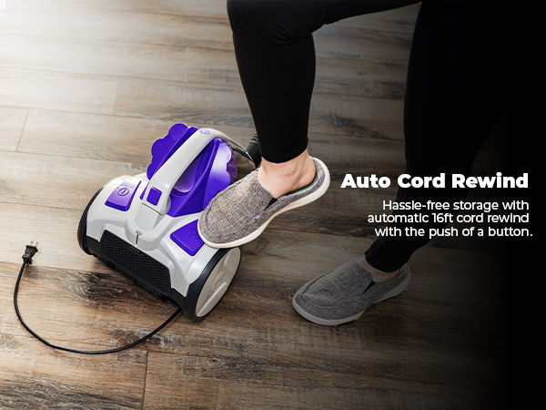 Person's foot pressing a vacuum's auto cord rewind button on a wooden floor.
