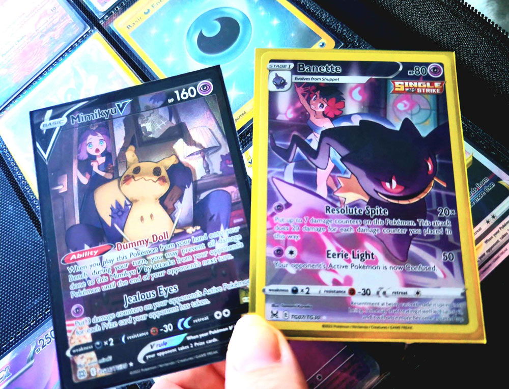 Two Pokémon trading cards held in a hand.