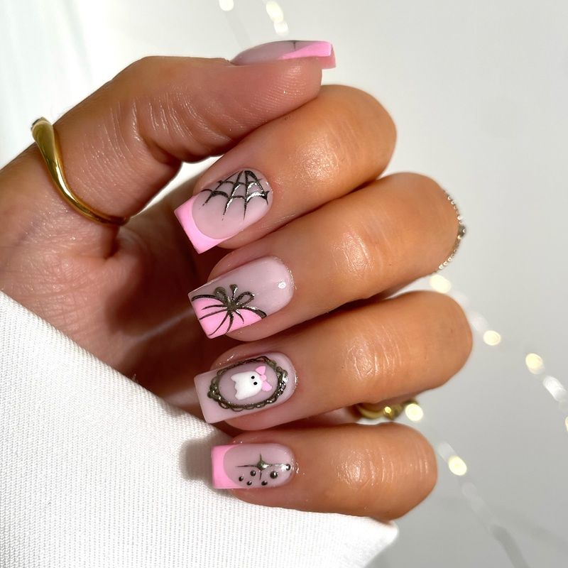 A hand with pink and clear nails featuring spider web designs.
