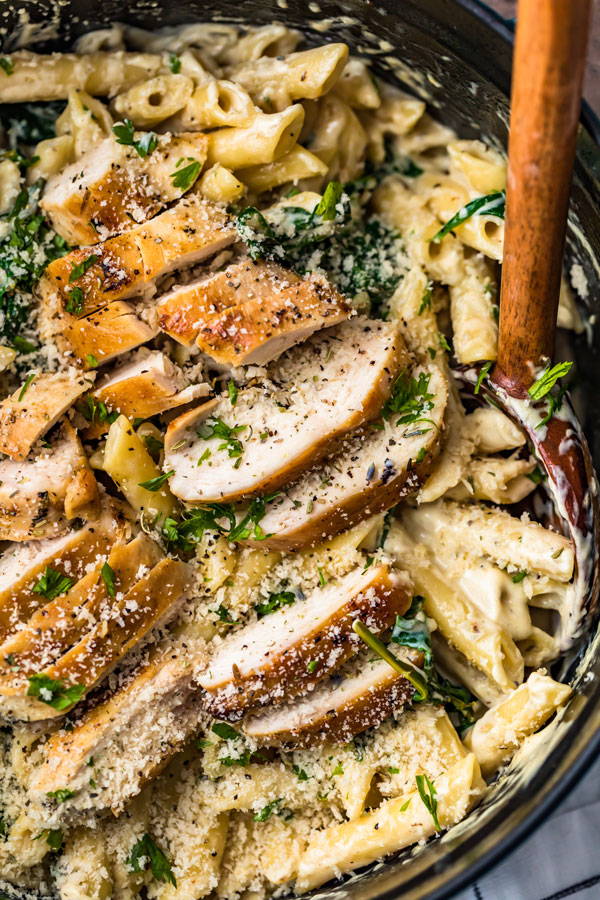 Pasta in a creamy cheesy sauce topped with grilled chicken and prepared in a skillet
