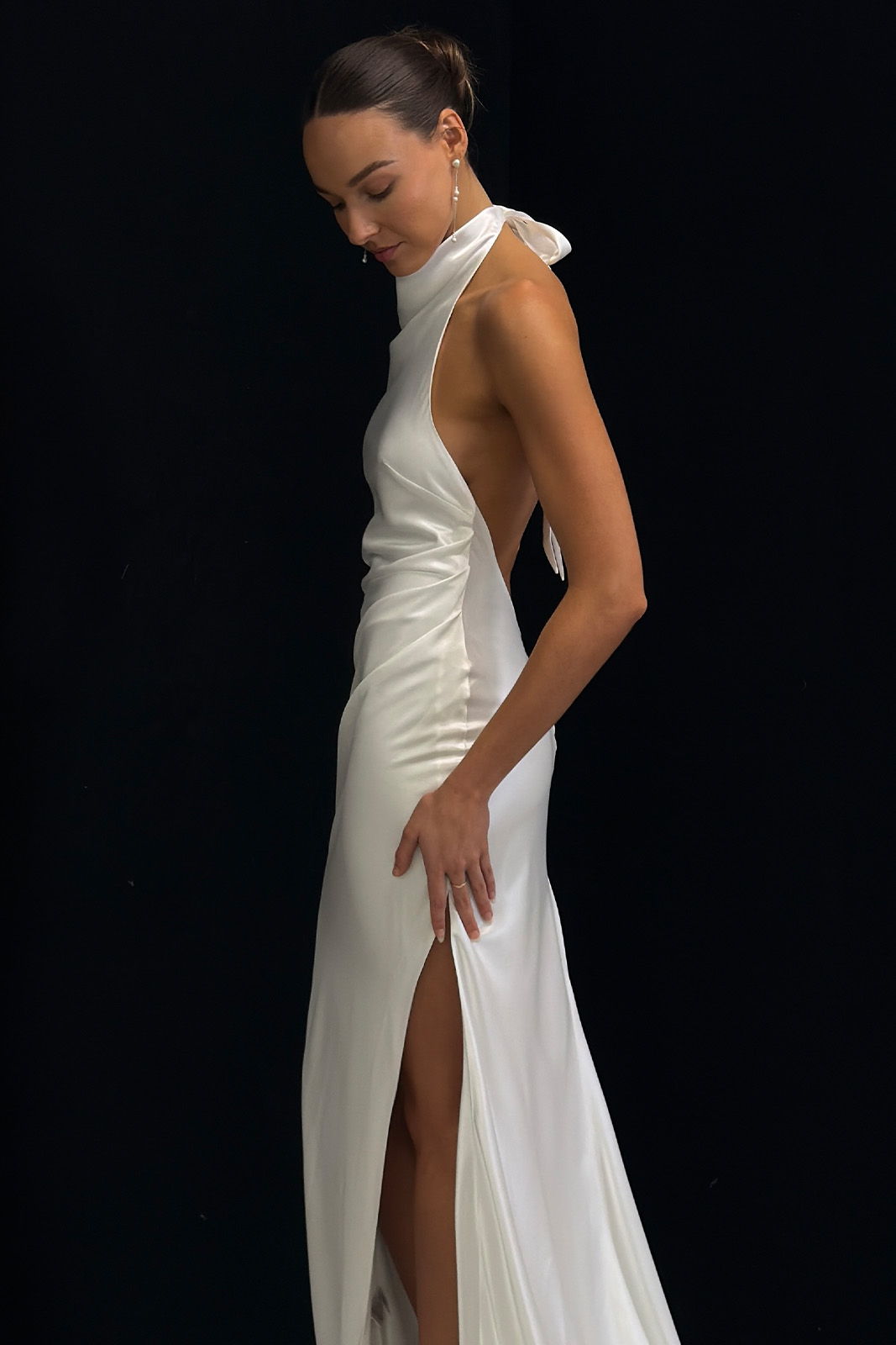 A woman in a sleek, white evening dress with a thigh-high slit.