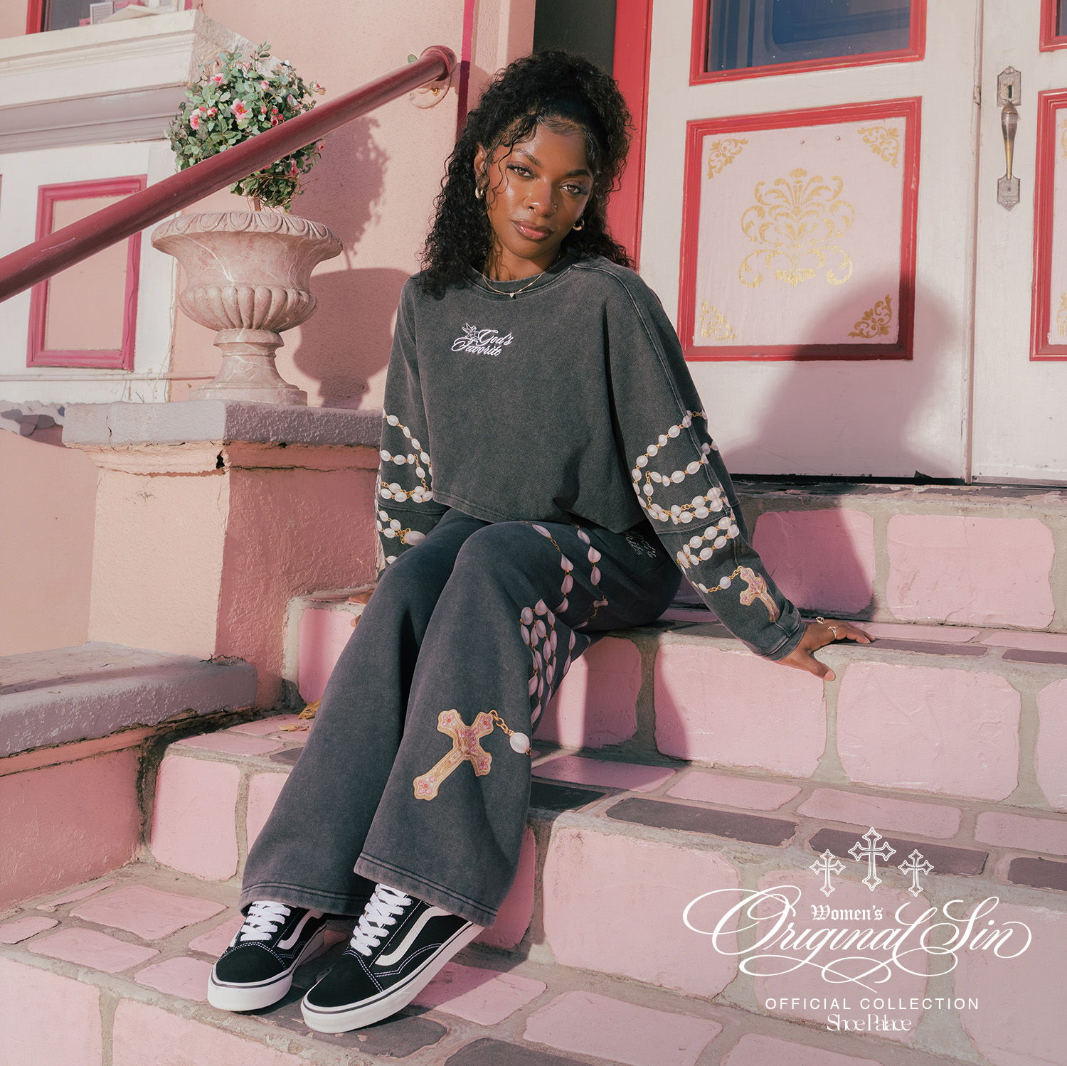 Young woman sitting on steps, wearing stylish gray outfit and sneakers.