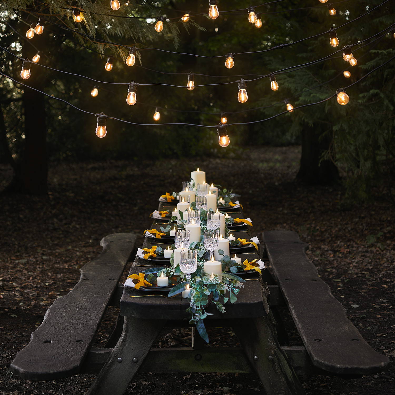 Wedding table with assortment of TruGlow candles and garland styled as part of centrepiece with festoons hung above table