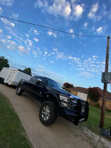 Malachi's black 2012 Ford F250 with brush guard towing a white enclosed trailer on a driveway