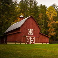 Red Barn surrounded by green lawn and forest