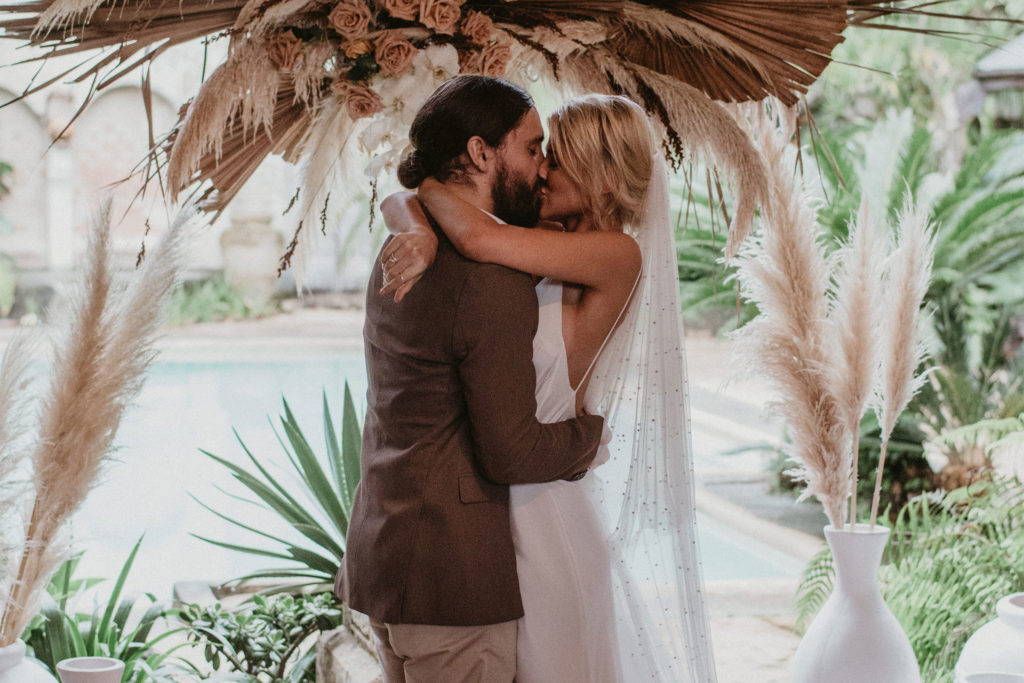 Grace Loves Lace bride wearing the Pearly long veil kissing her groom in brown suit