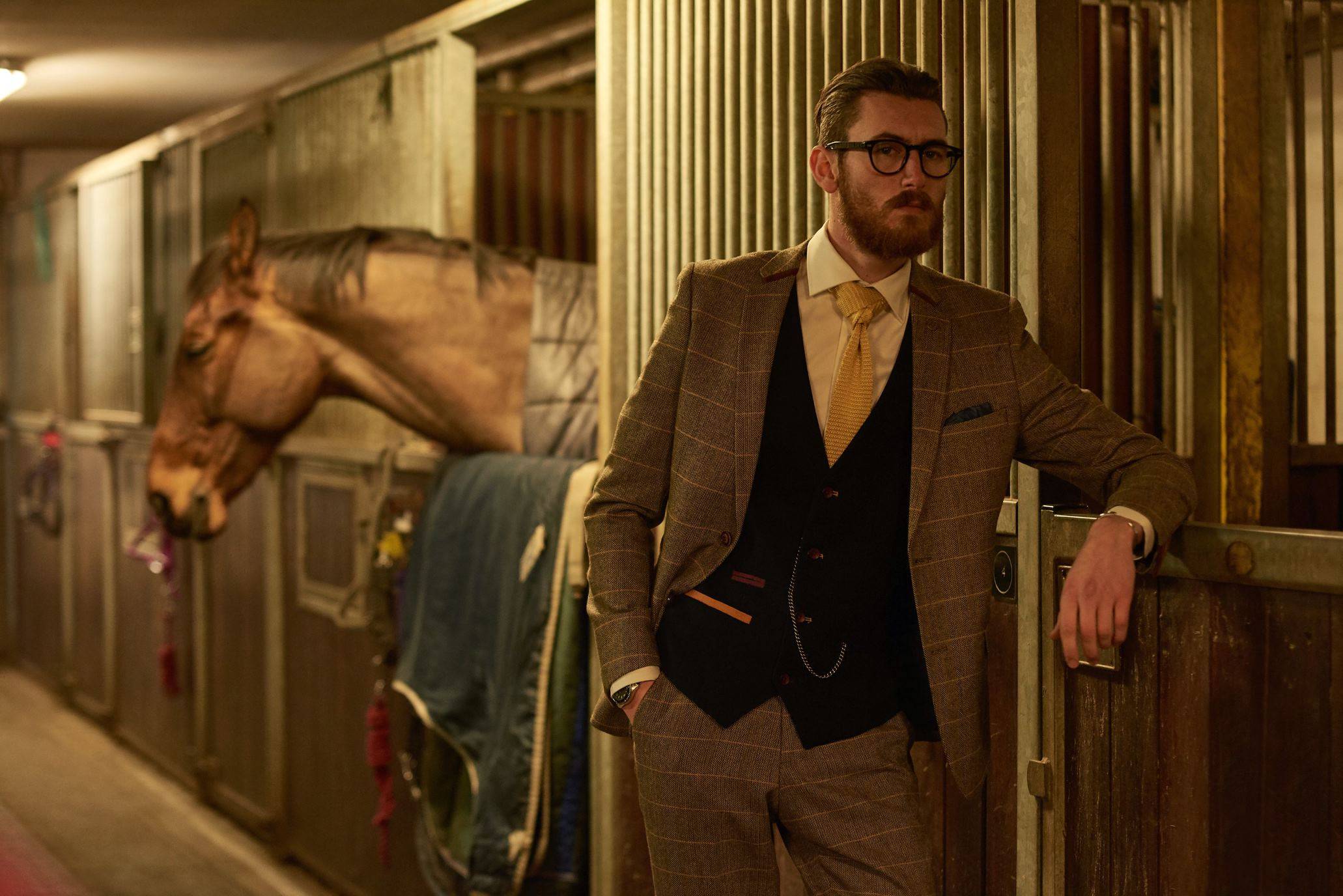 man wearing a tan tweed suit in cheltenham horse racing stable