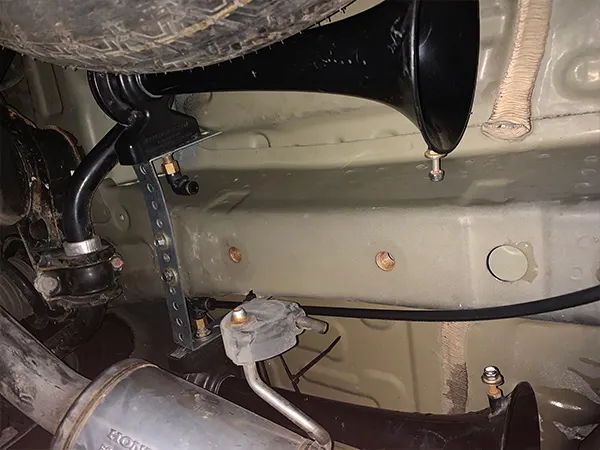 Close-up two black train horns mounted under Carrie's Acura MDX undercarriage with brass fittings photo 4