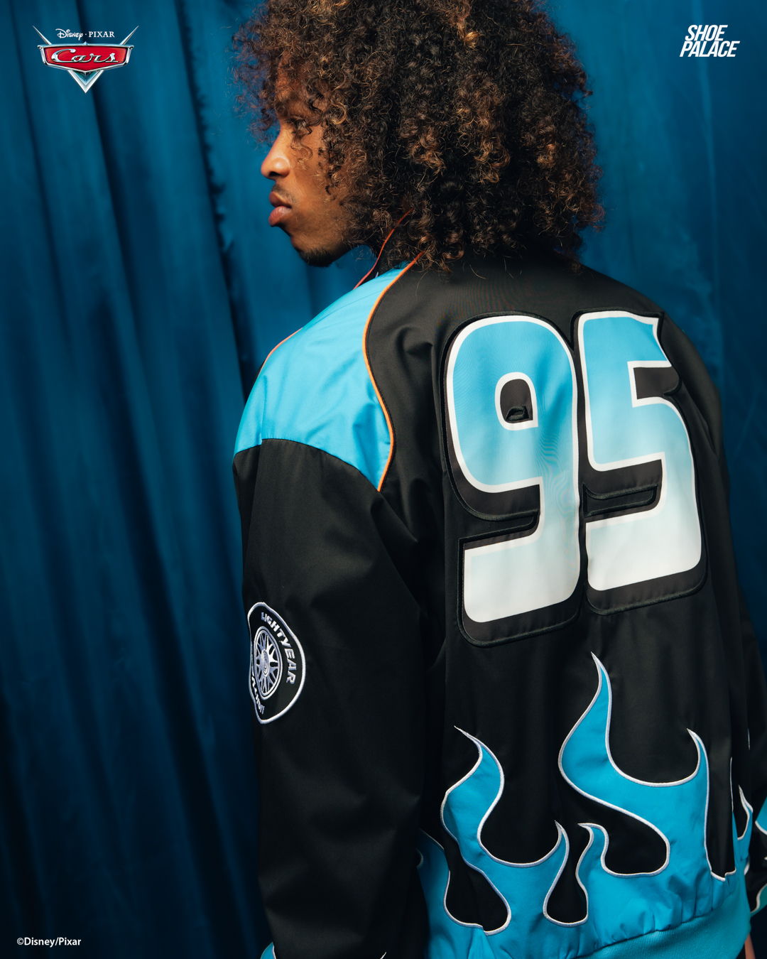 Person with curly hair wearing a jacket featuring the number 95.
