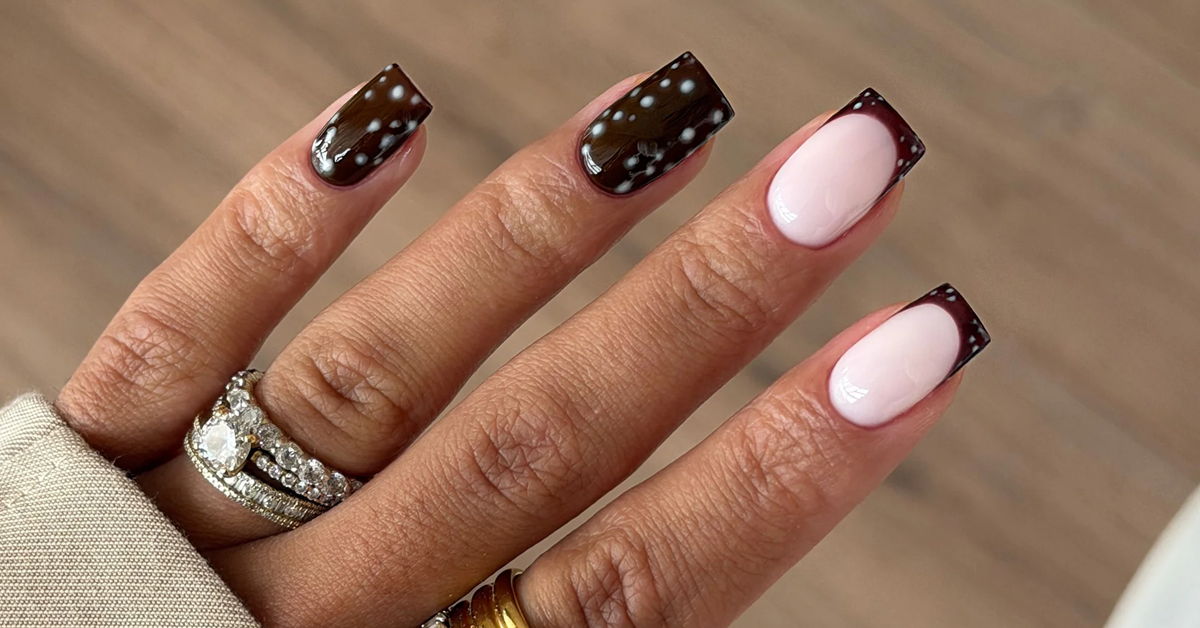 A hand with stylishly manicured nails in various colors and designs.