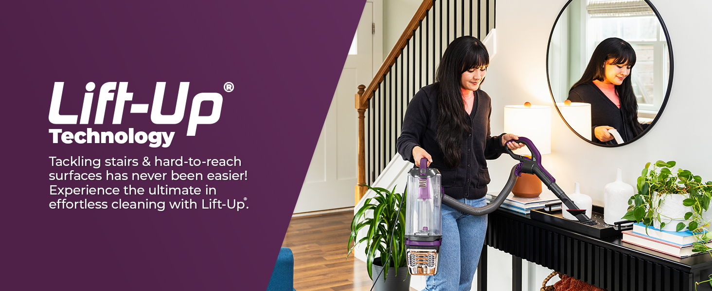 Woman using a vacuum cleaner in a home setting with a mirror reflection.