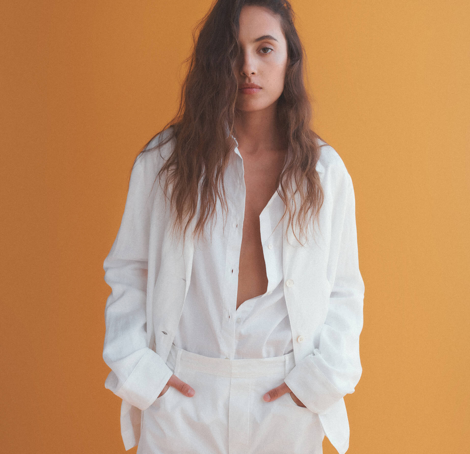 Woman with all white outfit with hands in pockets