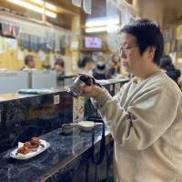 Person taking a photo of food in a restaurant setting.