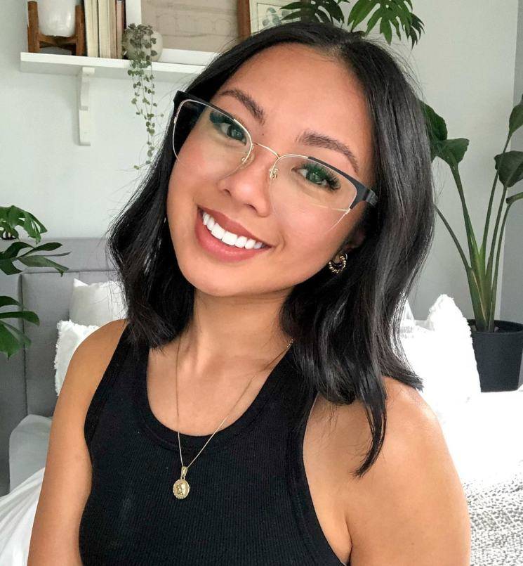 Woman with small face wearing Enchanted Gold Eyeglasses, semi-rimless cat eye frame and a black tank top with gold necklace and earrings 