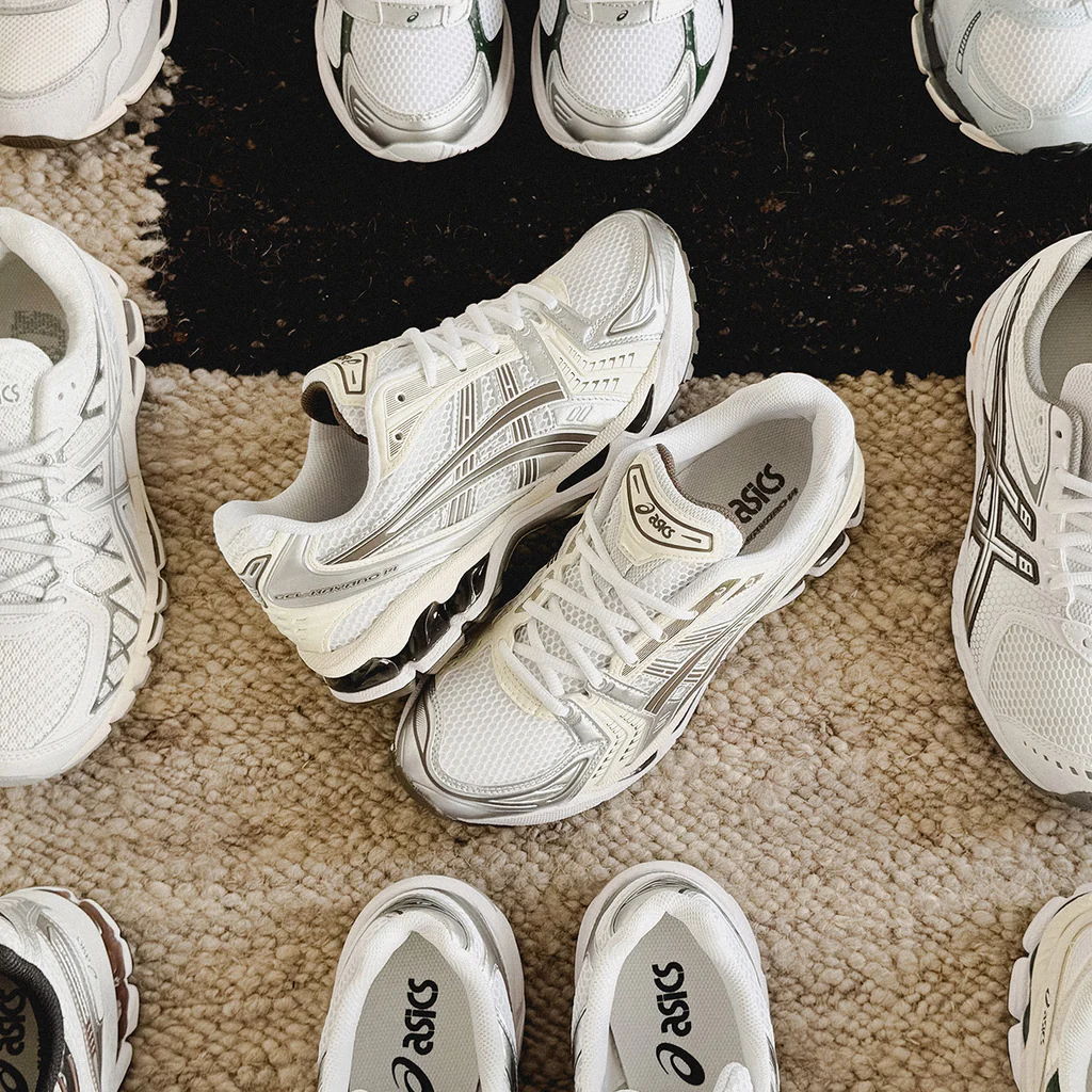 Various white athletic shoes arranged on a carpet.