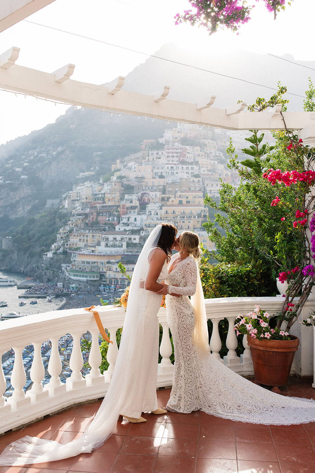 Brides sharing a kiss on a balcony in Positano, Italy
