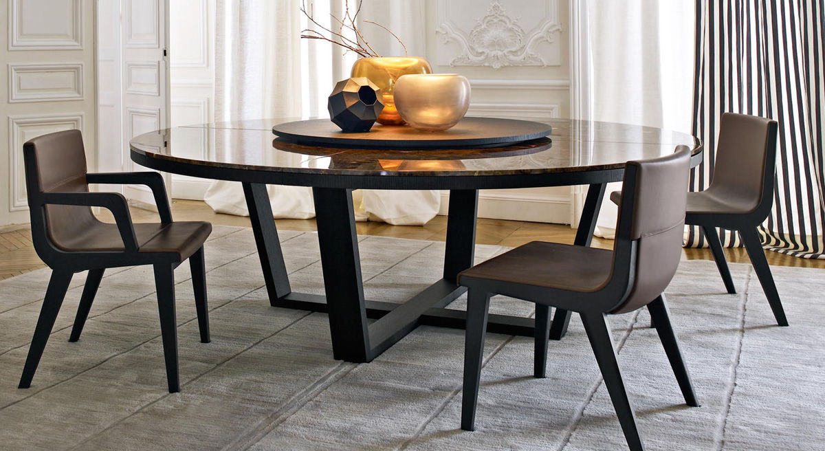 Round Maxalto dining table with four chairs in an elegant setting.