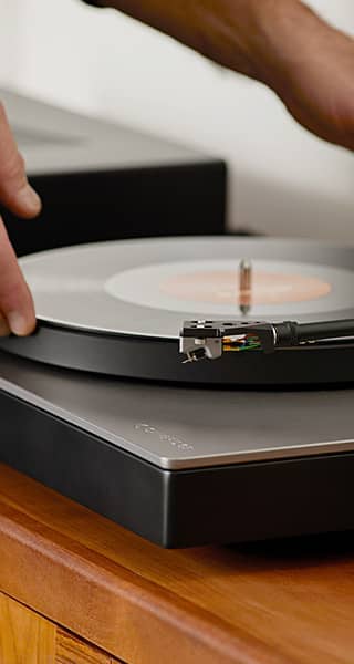 Person placing a vinyl record on a turntable.