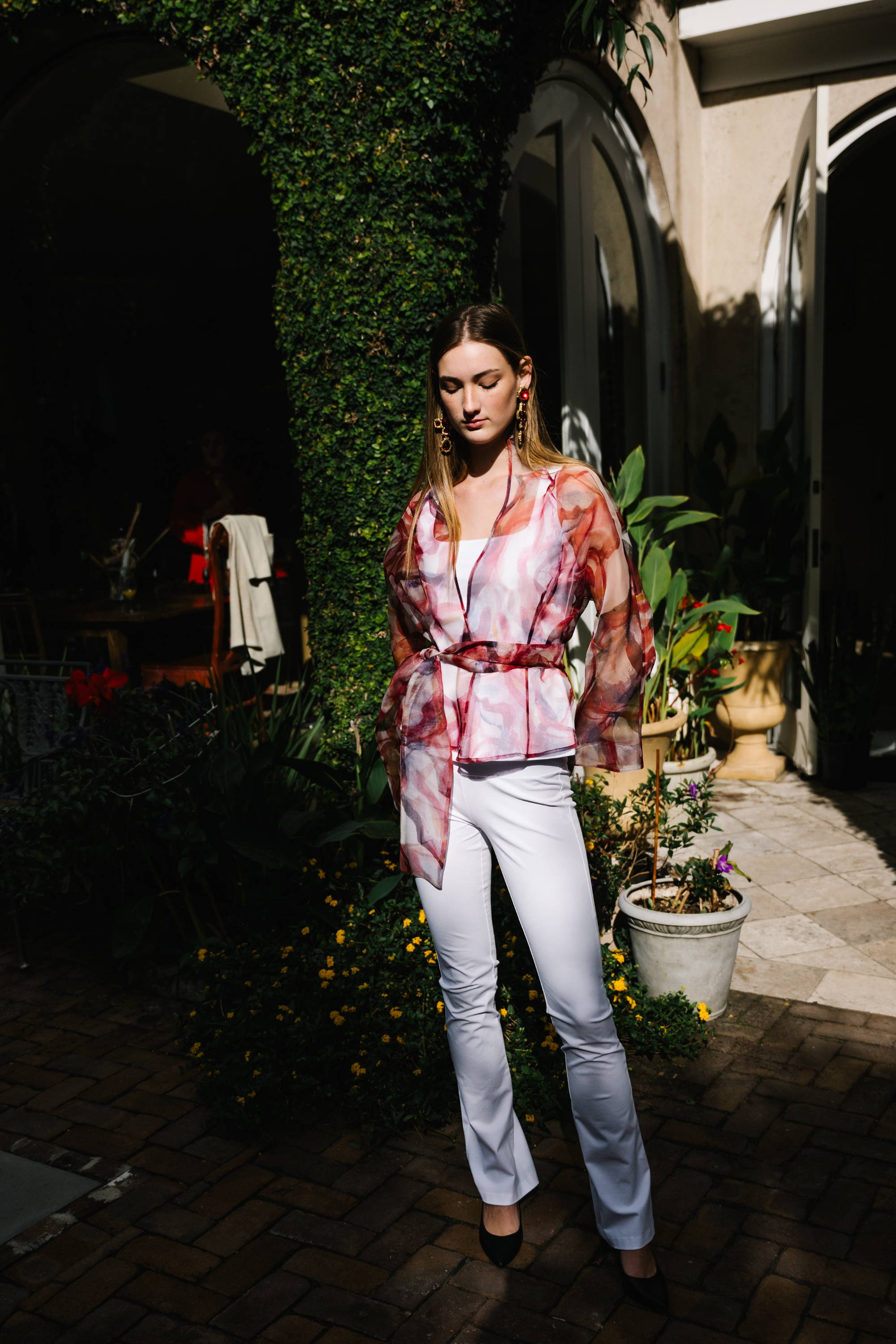 Woman wearing rose printed organza shirt over white stretch cotton tank top and pants by Ala von Auersperg