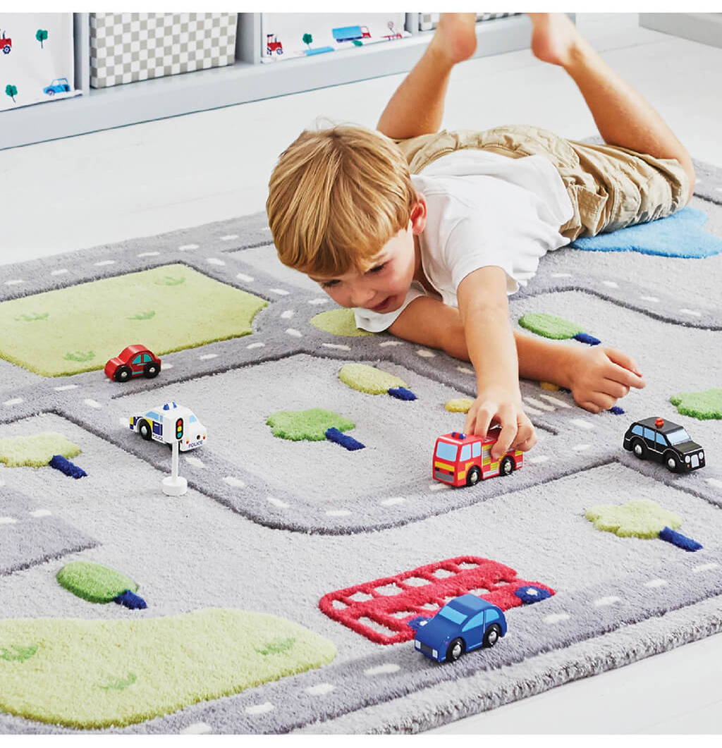 Young boy playing with toy cars on On the Road Rug