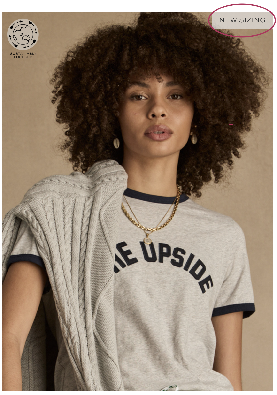 Woman with curly hair wearing a gray shirt and a sweater.