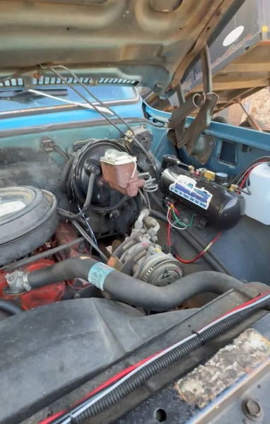 Engine bay view of Sammy's 1976 Chevy K10 showing the onboard air compressor mounted near the firewall, install photo 1