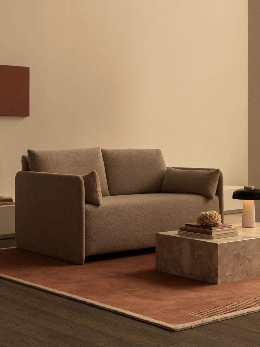 A modern living room featuring a brown Offset sofa bed by Audo Copenhagen and a Pinth coffee table.
