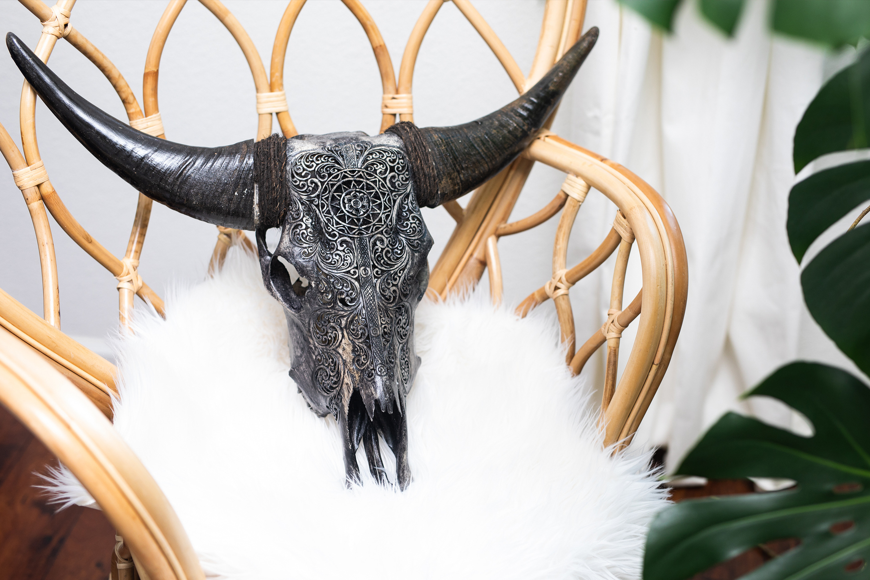 A carved grey skull placed on a white pillow on a chair. 