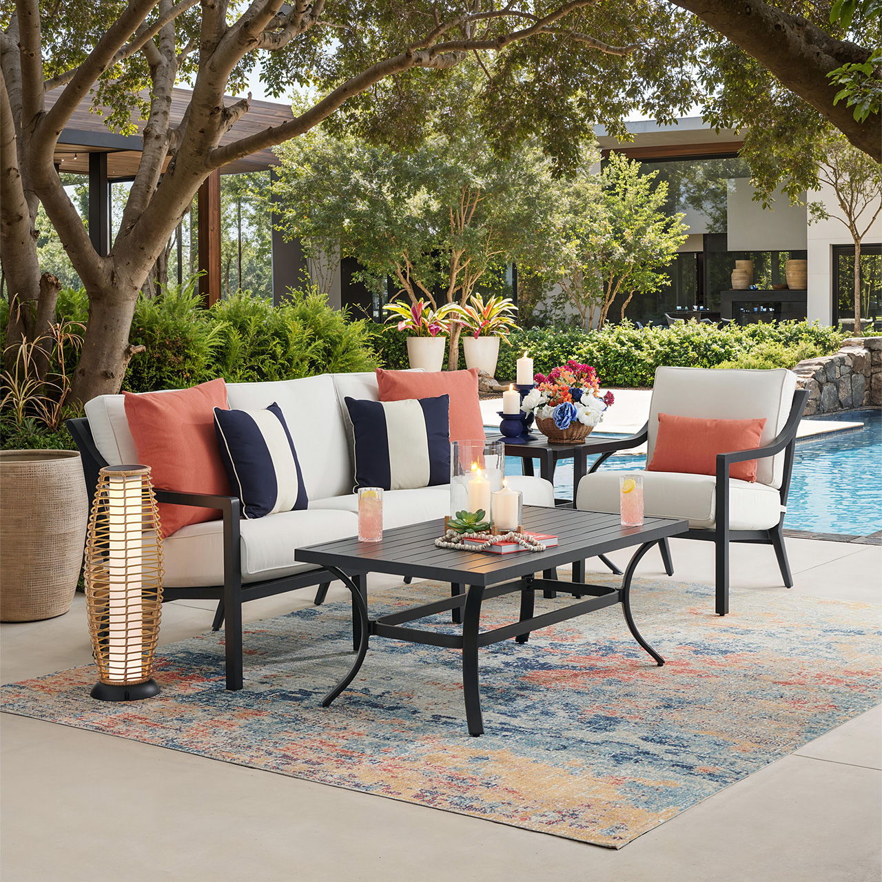 Outdoor seating area with a table, cushions, and pool in the background.