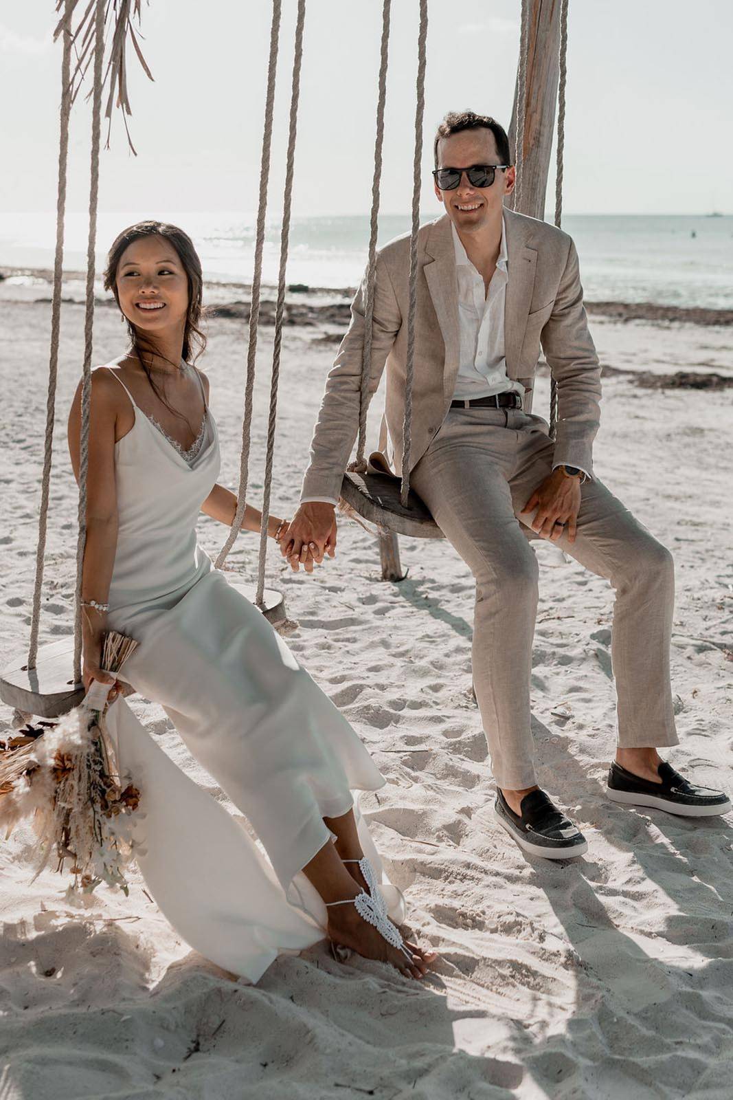 Bride and groom, sitting on a beach swing