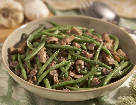 Bowl of green beans with mushrooms and garlic.