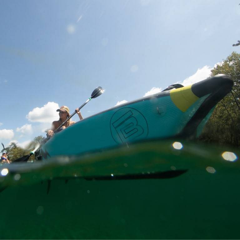 Looking up from the water at someone paddling the DEUS Aero Native Citron