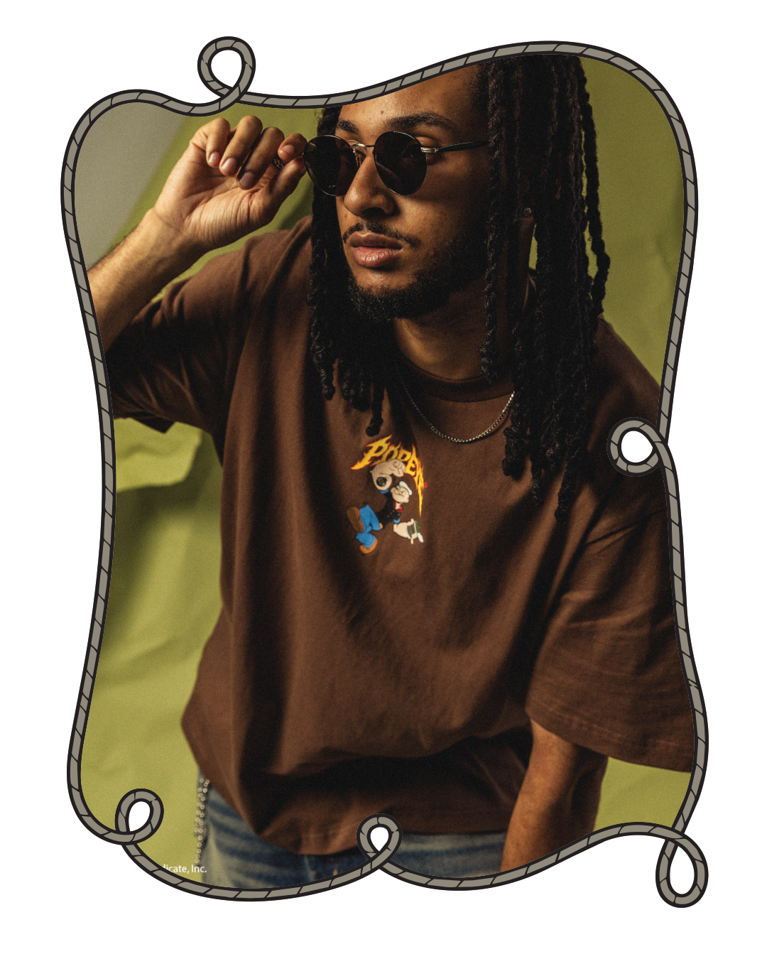 Person wearing sunglasses and a brown t-shirt, posing against a green background.