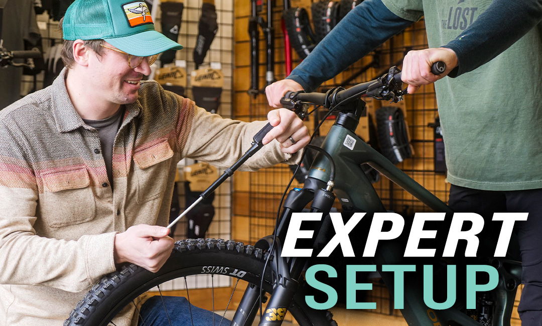 Person working on a bicycle setup in a shop environment.