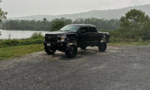 Tanner's lifted black Ford F-150 crew cab parked on gravel with misty hills and a lake in the background