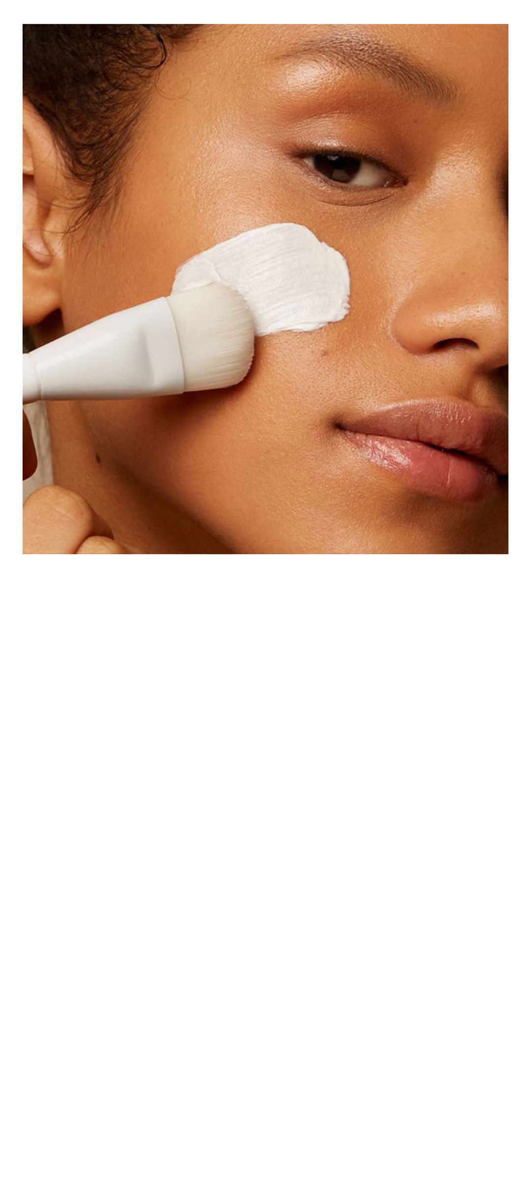 Person applying cream to their face with a brush.