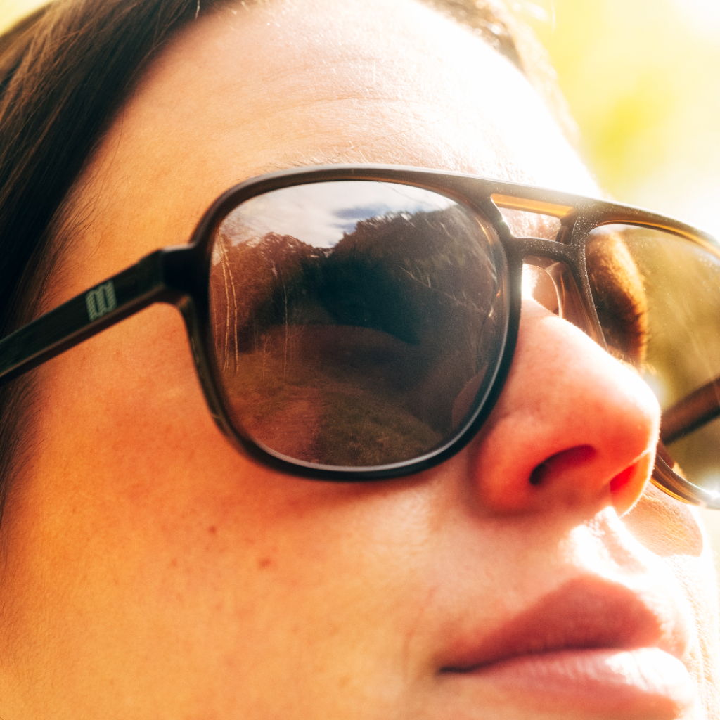 Close-up of a person wearing sunglasses with a blurred background.