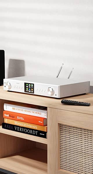 A white tuner on a wooden table with books and a remote.