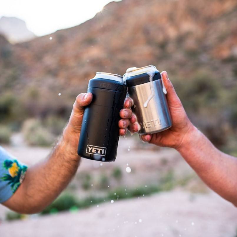 A lifestyle image of two people doing a cheers with Yeti tumblers.