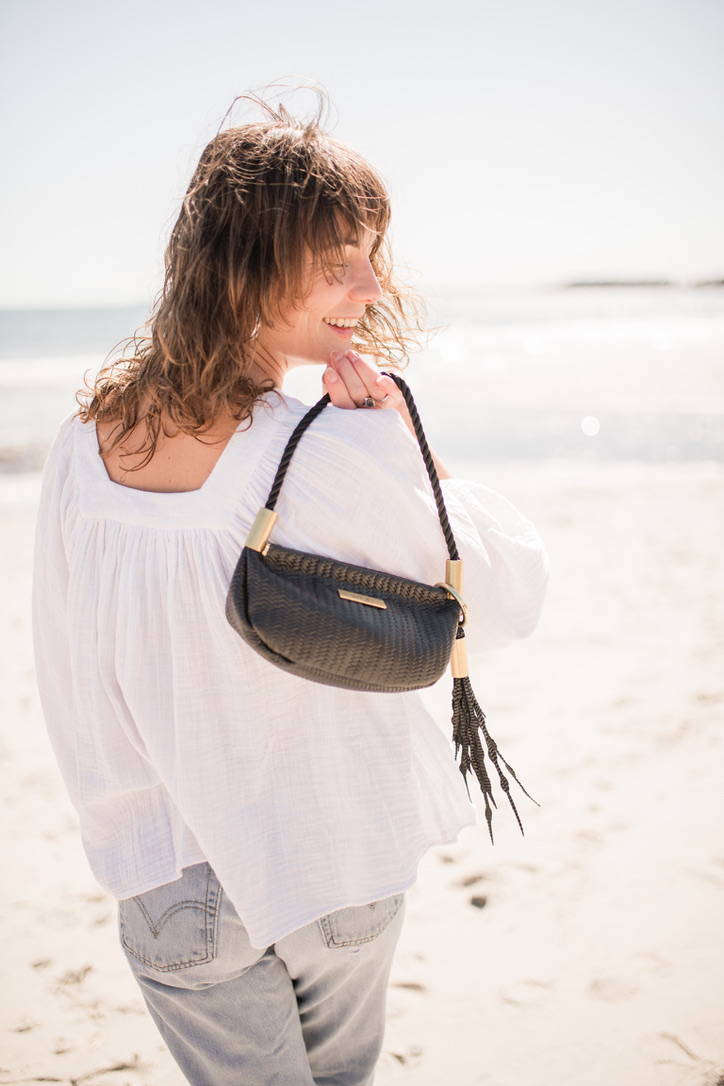woman holding black basketweave leather clam shell bag
