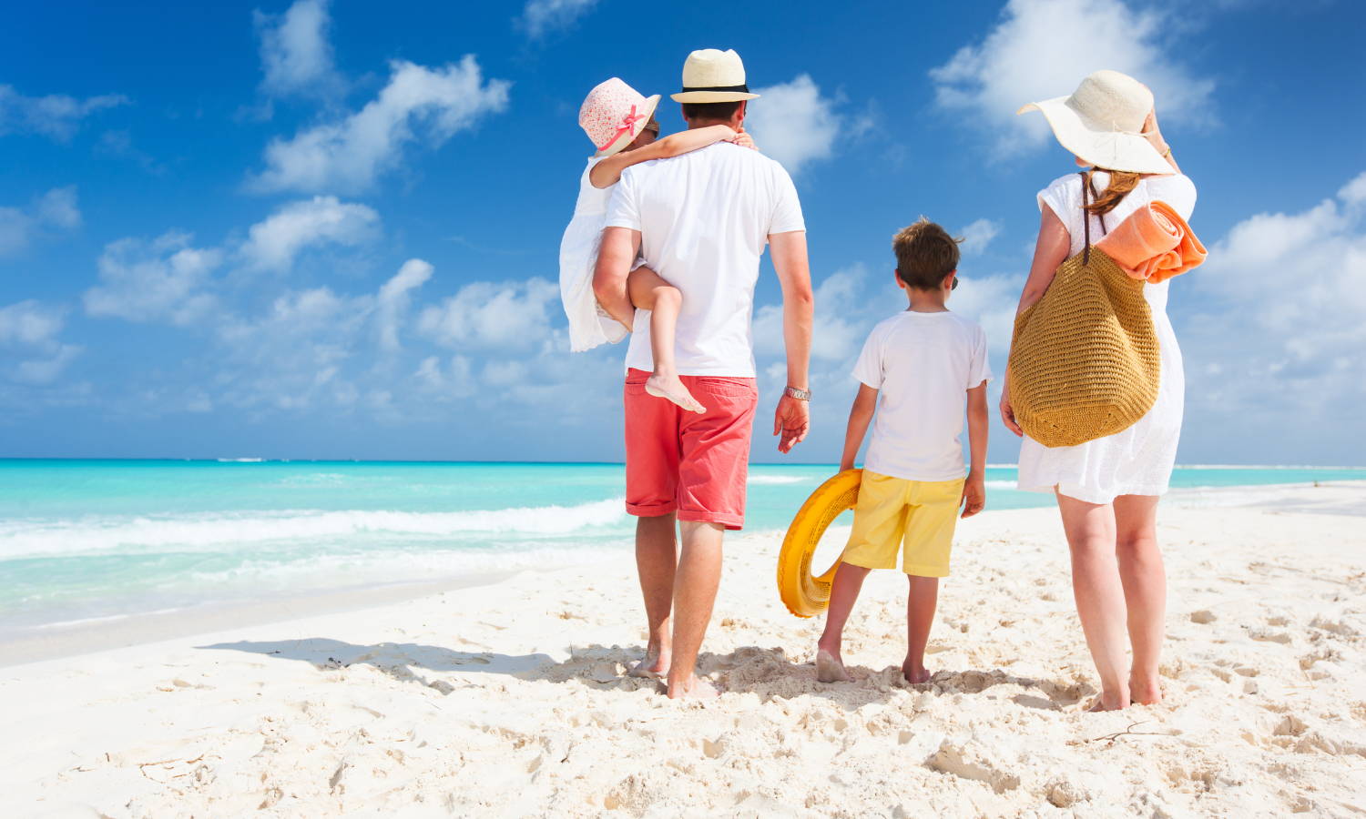 family of four walking away from the camera on a white sandy beach