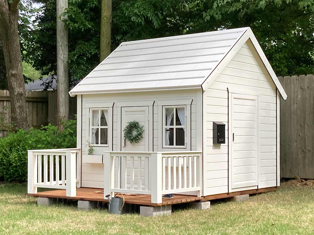 Wooden Playhouse Snowy Owl with black trims, wooden terrace and flower boxes in the garden by WholeWoodPlayhouses