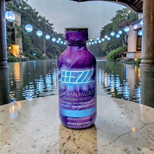 Purple beverage bottle with reflective surface and serene outdoor setting.