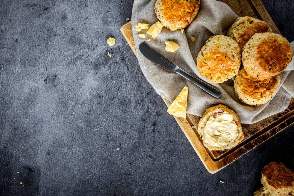 Cheese and beer scones on a serving board with a knife and bits of cheese.