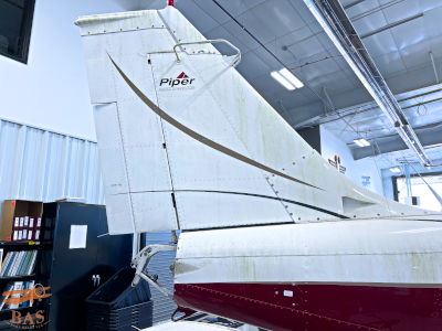 Tail of an aircraft inside a hangar, showing details and markings.
