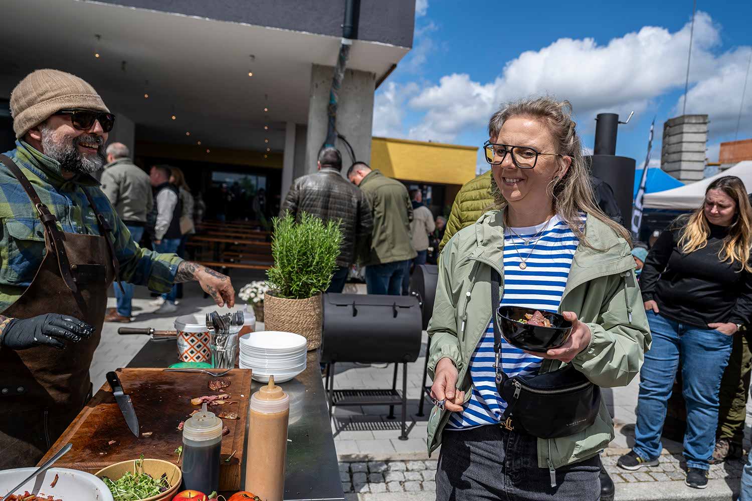 People enjoying food at an outdoor market. Bright, sunny day.